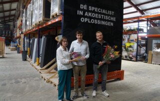 Wethouder Ria Leliveld overhandigt het bordje met de bloemen namens WerkgeversServicepunt Achterhoek aan Erik Weenink en Peter Nijhuis (rechts) van Nyink.